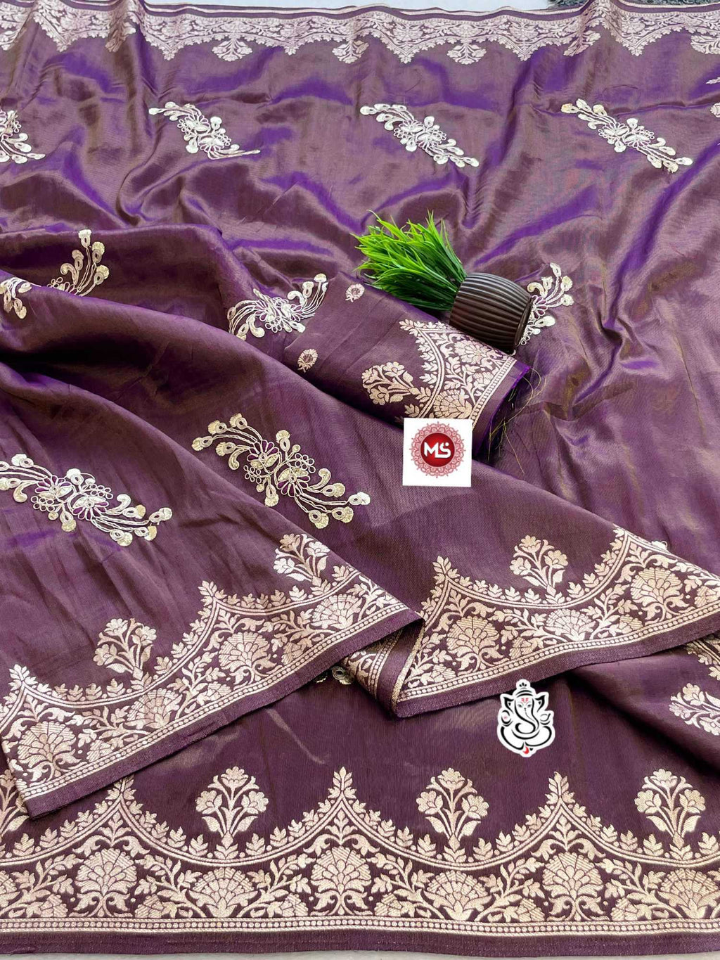 Purple fabric with gold embroidery and a brand logo in the center.