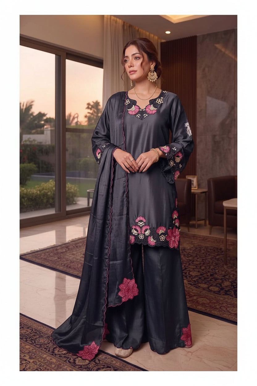 A two-panel catalog image showing a woman modeling a dark charcoal gray three-piece traditional outfit with floral embroidery. The set includes a kurta, pants, and a dupatta.
