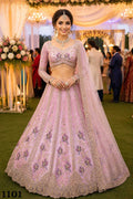 Woman in a pink and purple embroidered traditional outfit at a decorated event.
