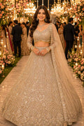 Woman in a traditional embroidered outfit at a decorated event with flowers and lights.