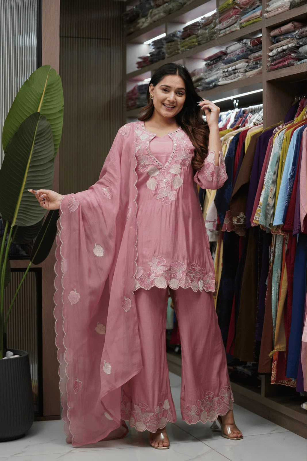 Woman in a pink traditional outfit standing in a clothing store.