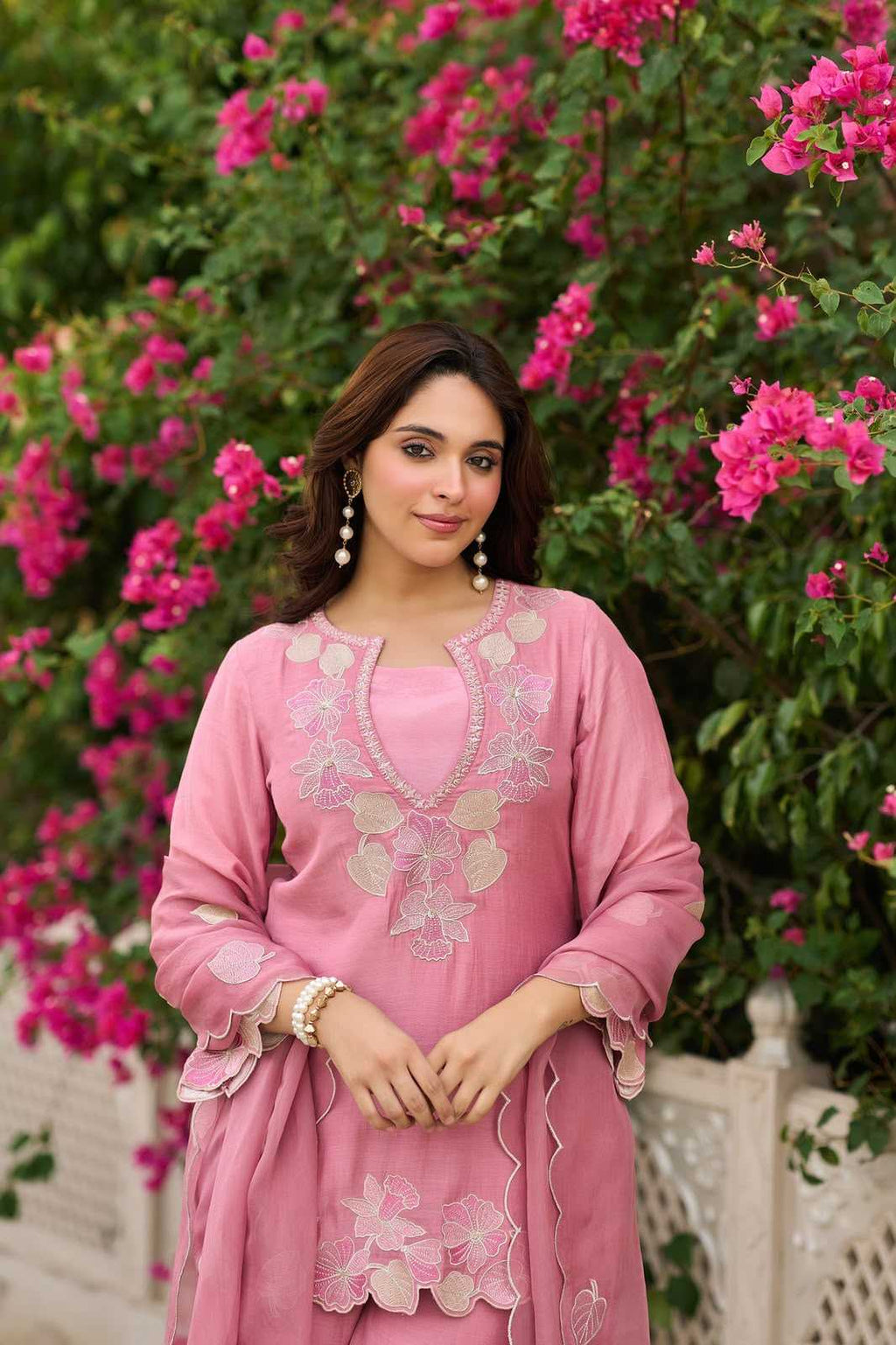 Woman in a pink traditional outfit standing in front of pink flowers