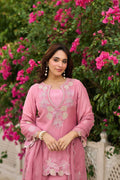 Woman in a pink traditional outfit standing in front of pink flowers