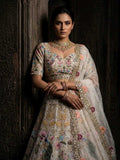 Woman in an embroidered traditional outfit with jewelry against a dark background