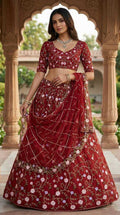 Woman in a red embroidered traditional outfit standing in an outdoor setting with architectural columns.