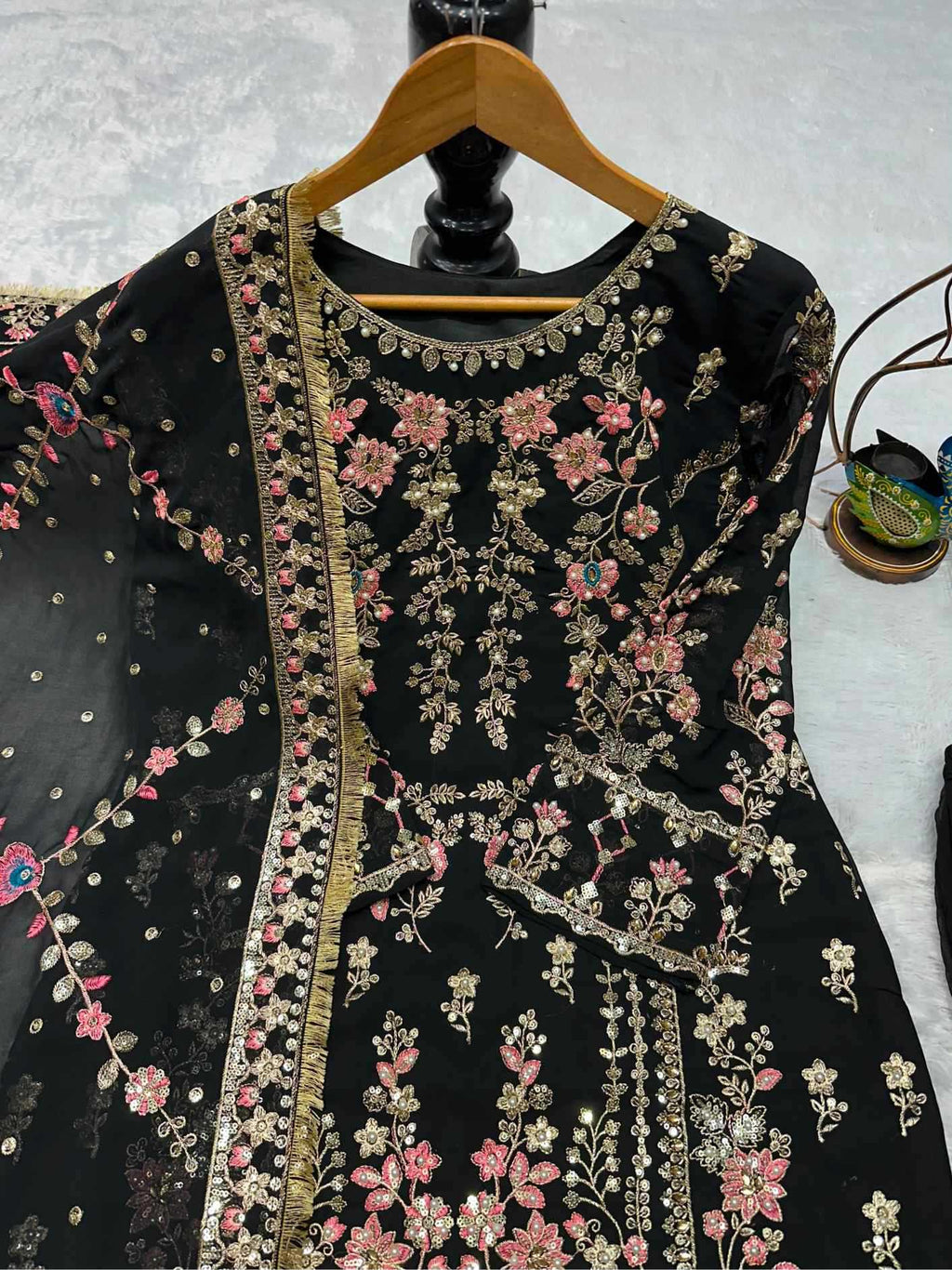 Black embroidered garment on a hanger against a white background