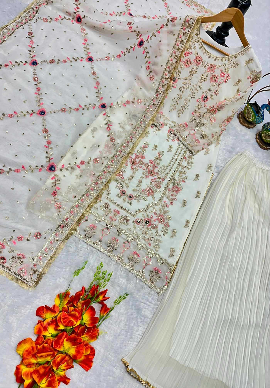 White embroidered outfit with floral patterns on a white background