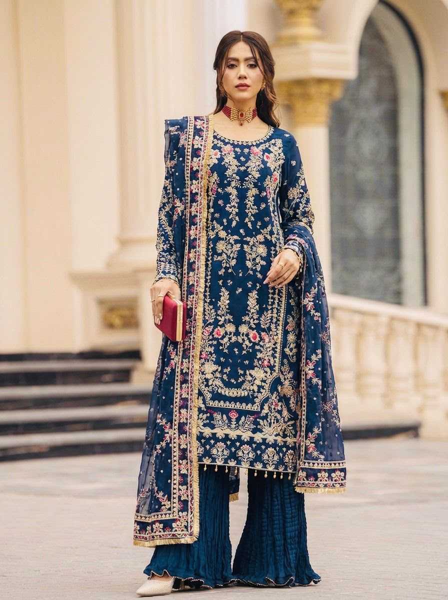 Woman in a blue embroidered traditional outfit standing in front of a building with architectural columns.