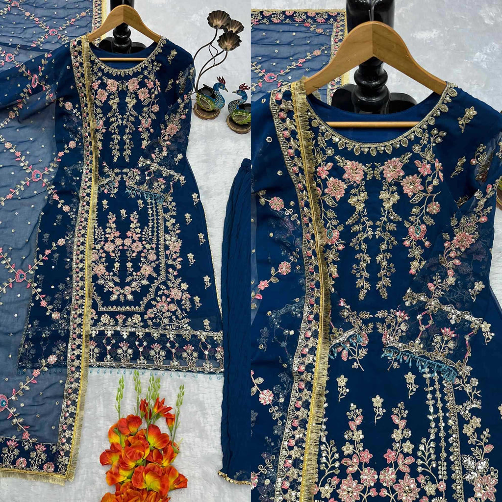A navy blue embroidered traditional dress displayed on a hanger, shown in a split view with a matching sheer dupatta. The dress features intricate floral embroidery in pink, gold, and green, with a gold border.