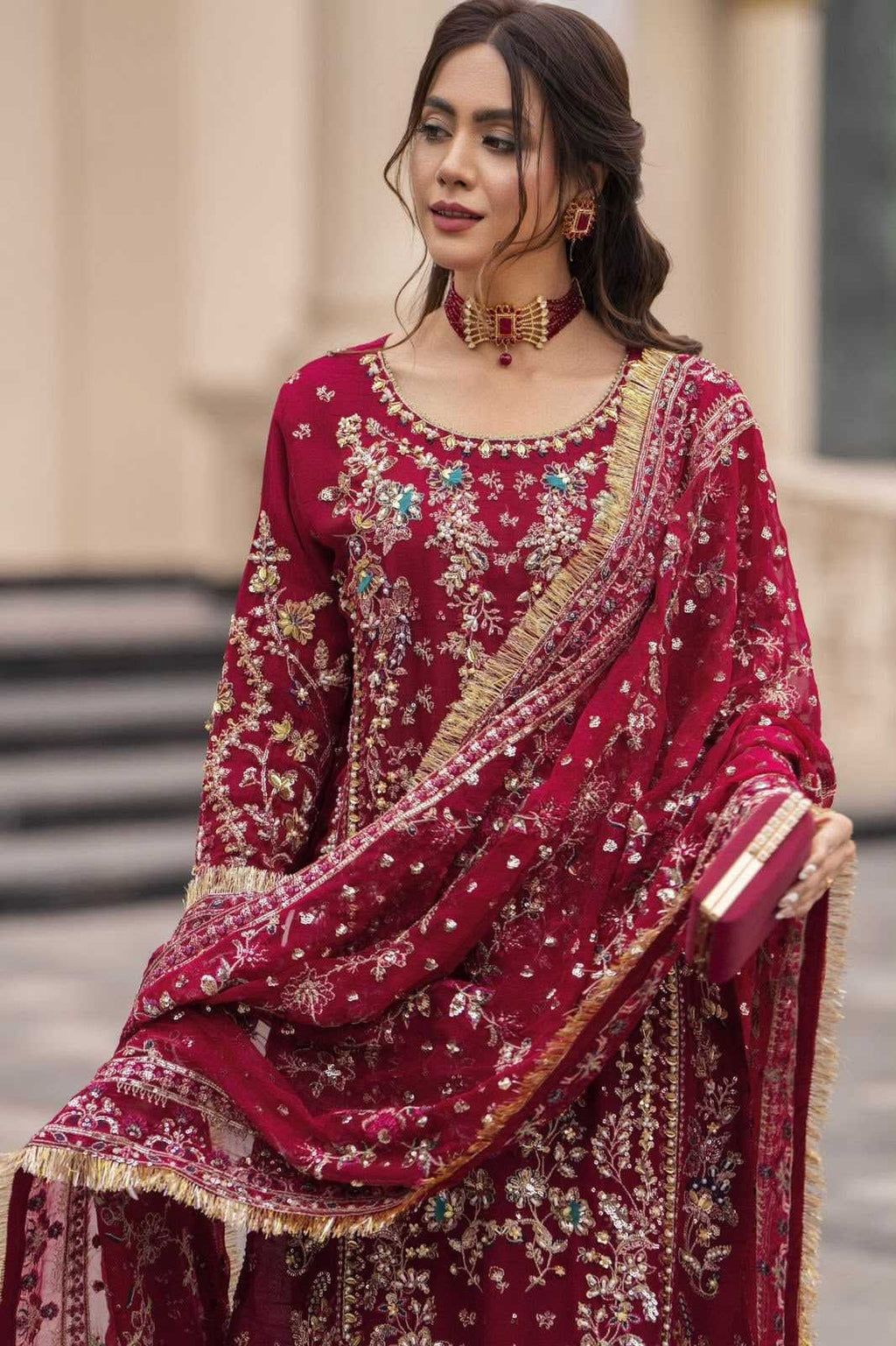 Woman in a red embroidered traditional outfit with gold details.