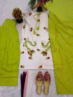 A women's traditional outfit laid flat on a white textured surface, featuring a white kurta with red and green floral embroidery and tie details, paired with bright lime green pants and a matching lime green scarf. A pair of floral embroidered flat shoes is also placed below.