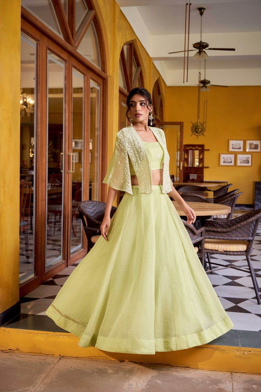 Woman in a light green traditional outfit standing in a restaurant with yellow walls and wooden furniture.