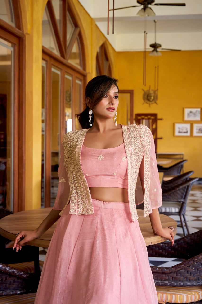 Woman in a pink traditional outfit with gold accents in a room with yellow walls and wooden furniture.