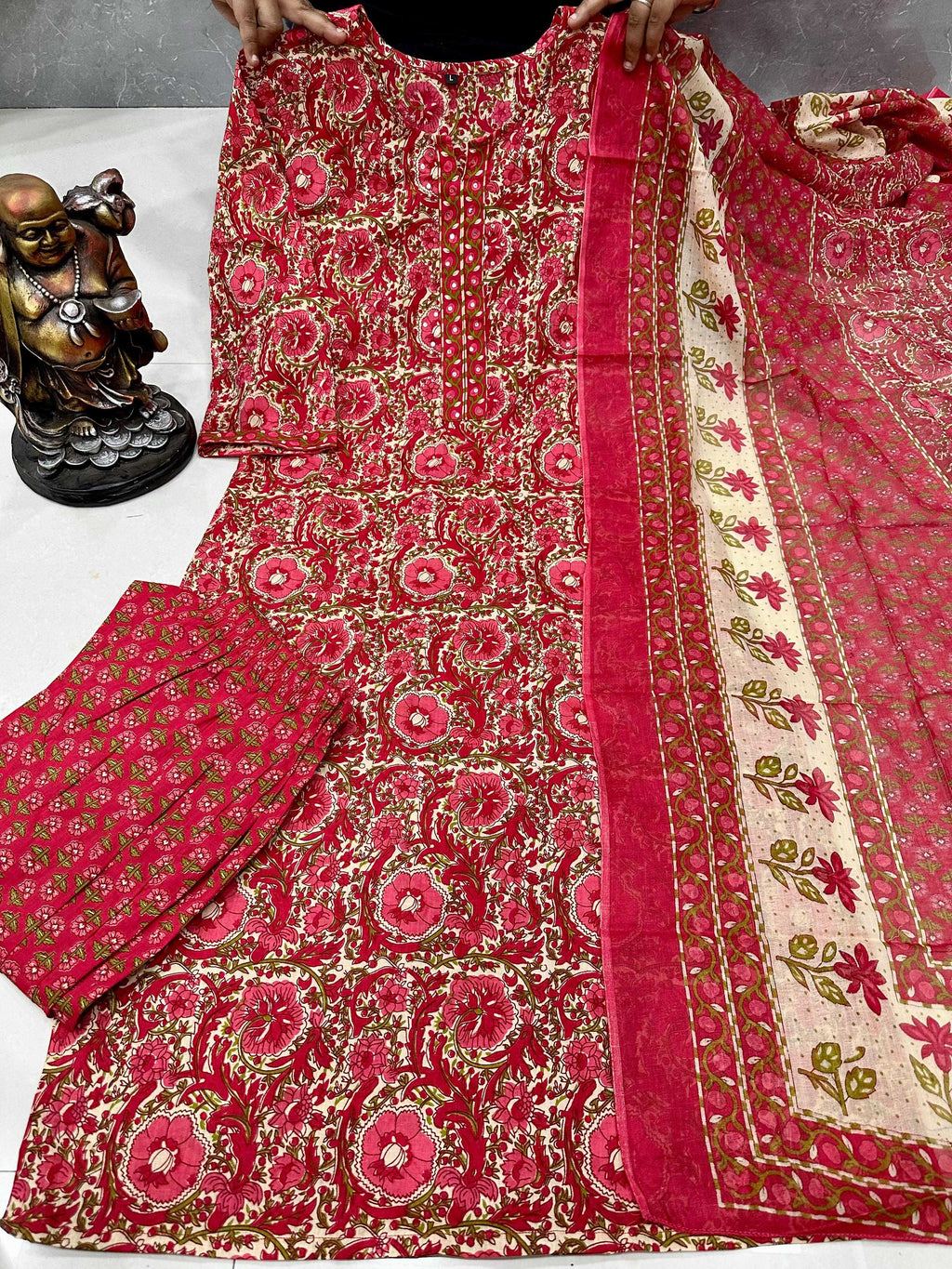 Red and gold patterned fabric with a statue in the background