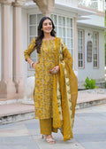 Woman in a yellow traditional outfit standing in front of a building.