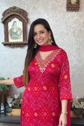 Woman wearing a red patterned dress in a room with decorative elements.