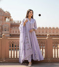 Woman in a light purple traditional outfit standing in front of a historic building.