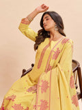 A woman models a yellow three-piece salwar kameez suit with pink floral embroidery and border detailing, seated on a wooden chair against a solid beige background.