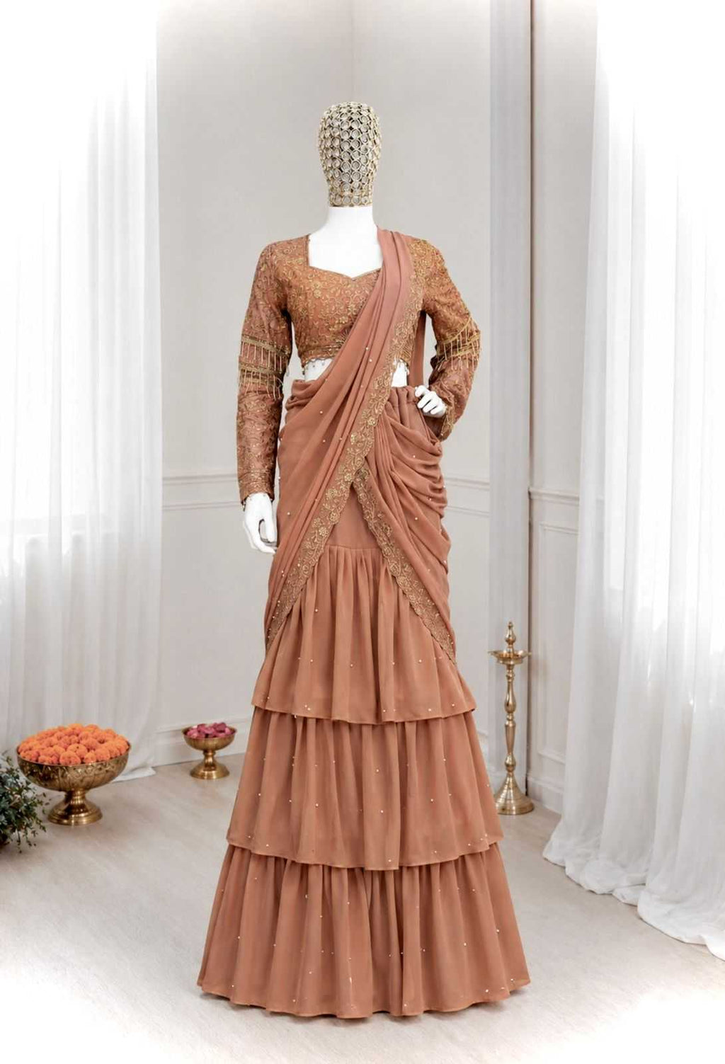 A terracotta-colored tiered lehenga choli set displayed on a mannequin in an indoor studio setting with white curtains.