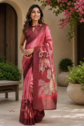 Woman wearing a pink saree with floral patterns in an outdoor setting