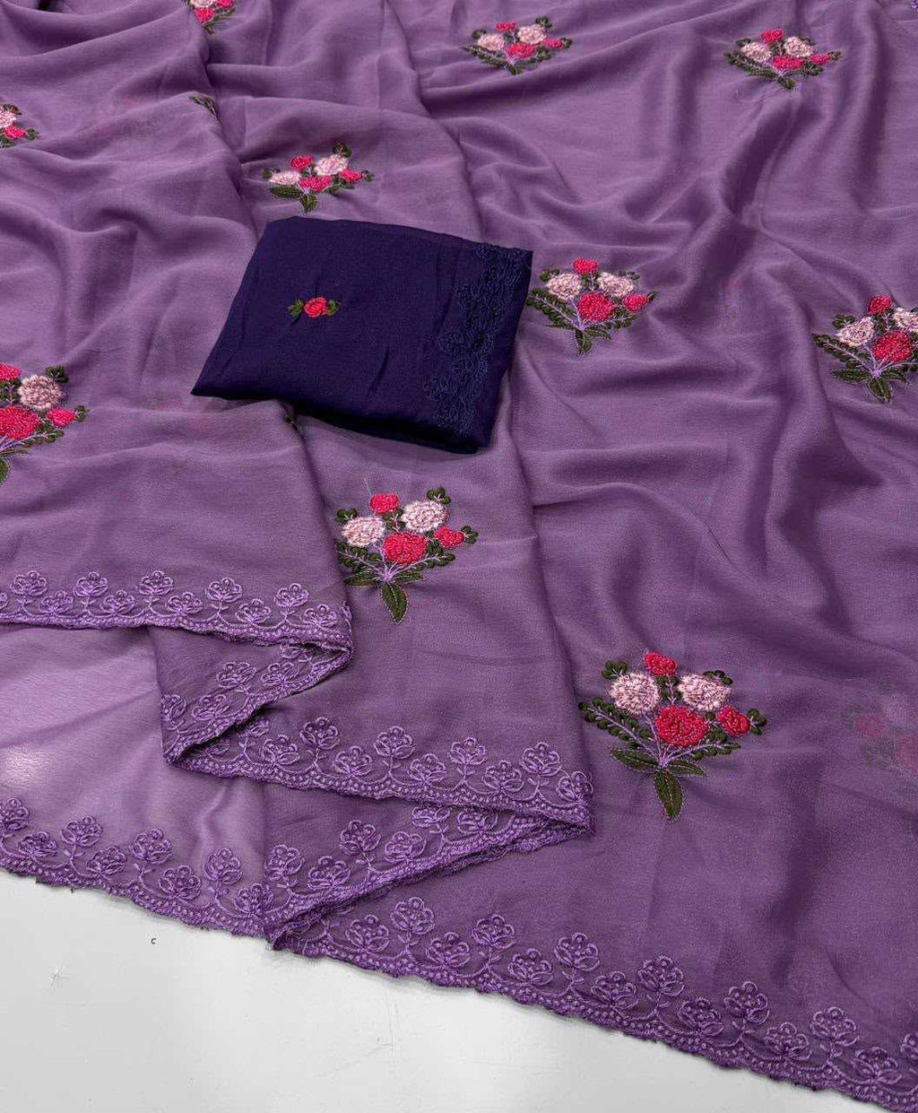 Purple embroidered fabric with floral motifs and a matching dark purple folded fabric piece on a white surface.