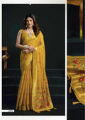 Woman wearing a yellow saree with floral patterns on a dark background