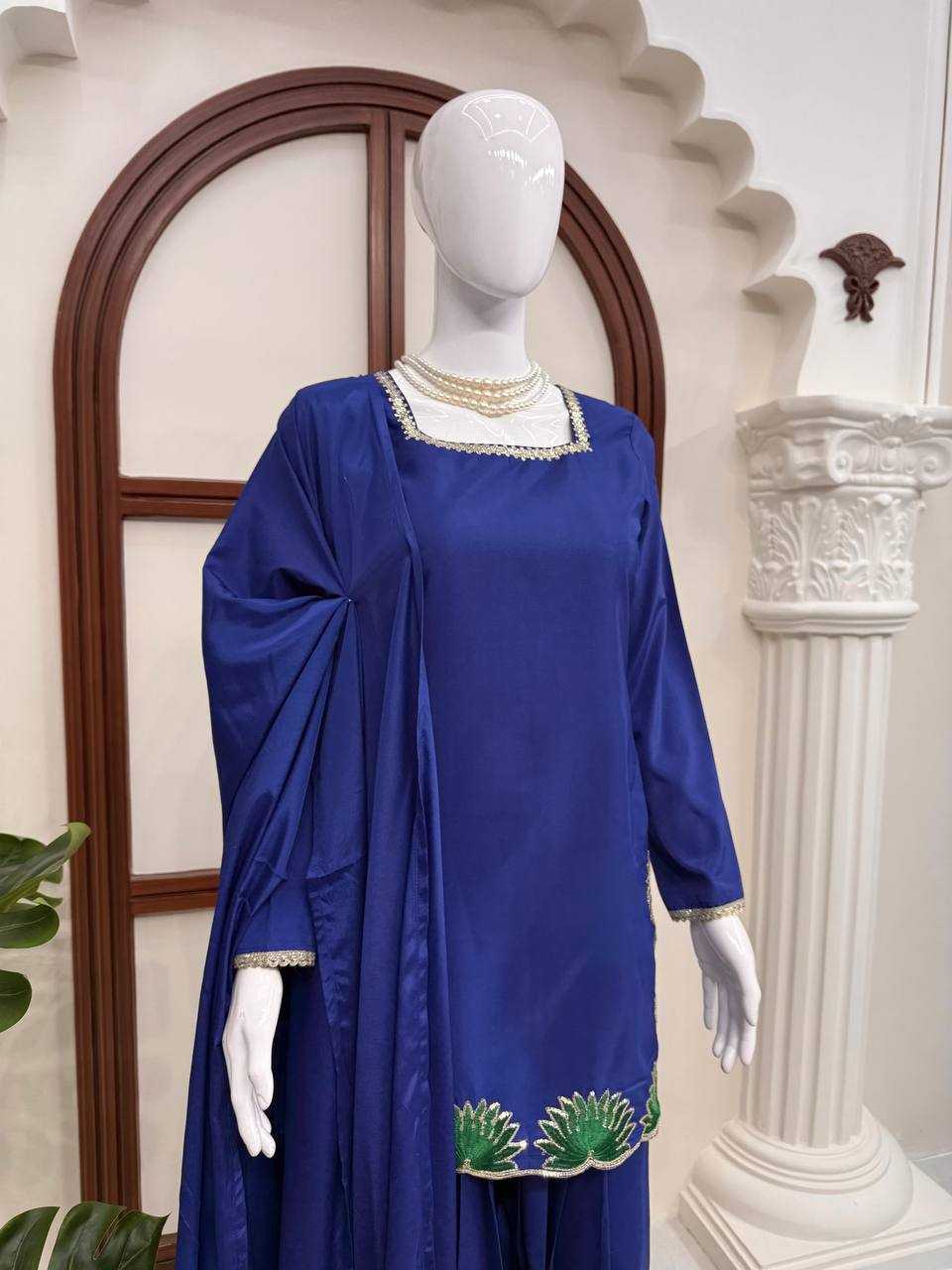 Mannequin wearing a blue dress with green embroidery in a decorative setting