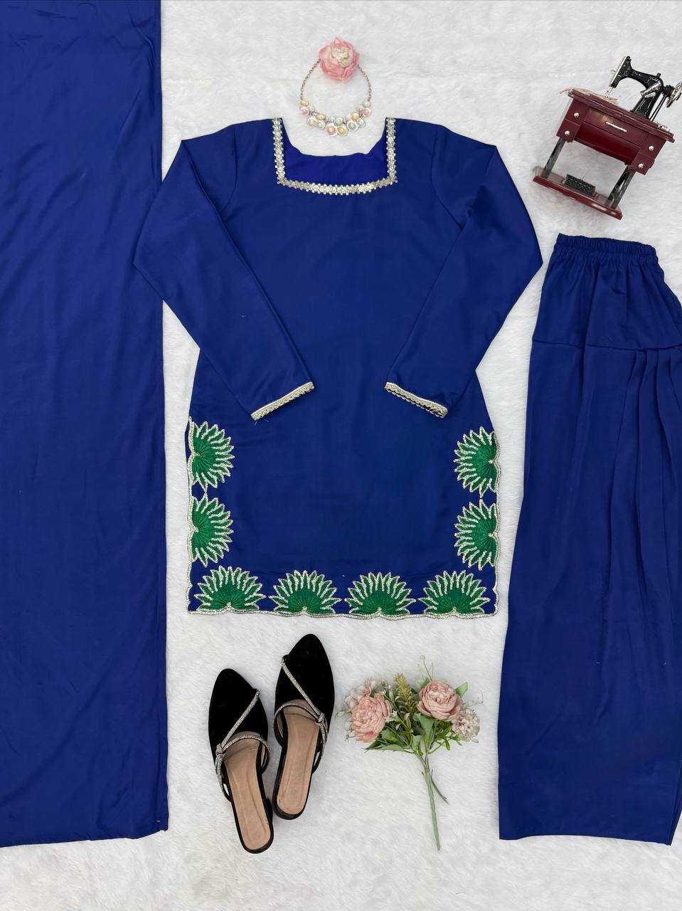 Blue embroidered outfit with matching pants, black shoes, and a sewing machine on a white background