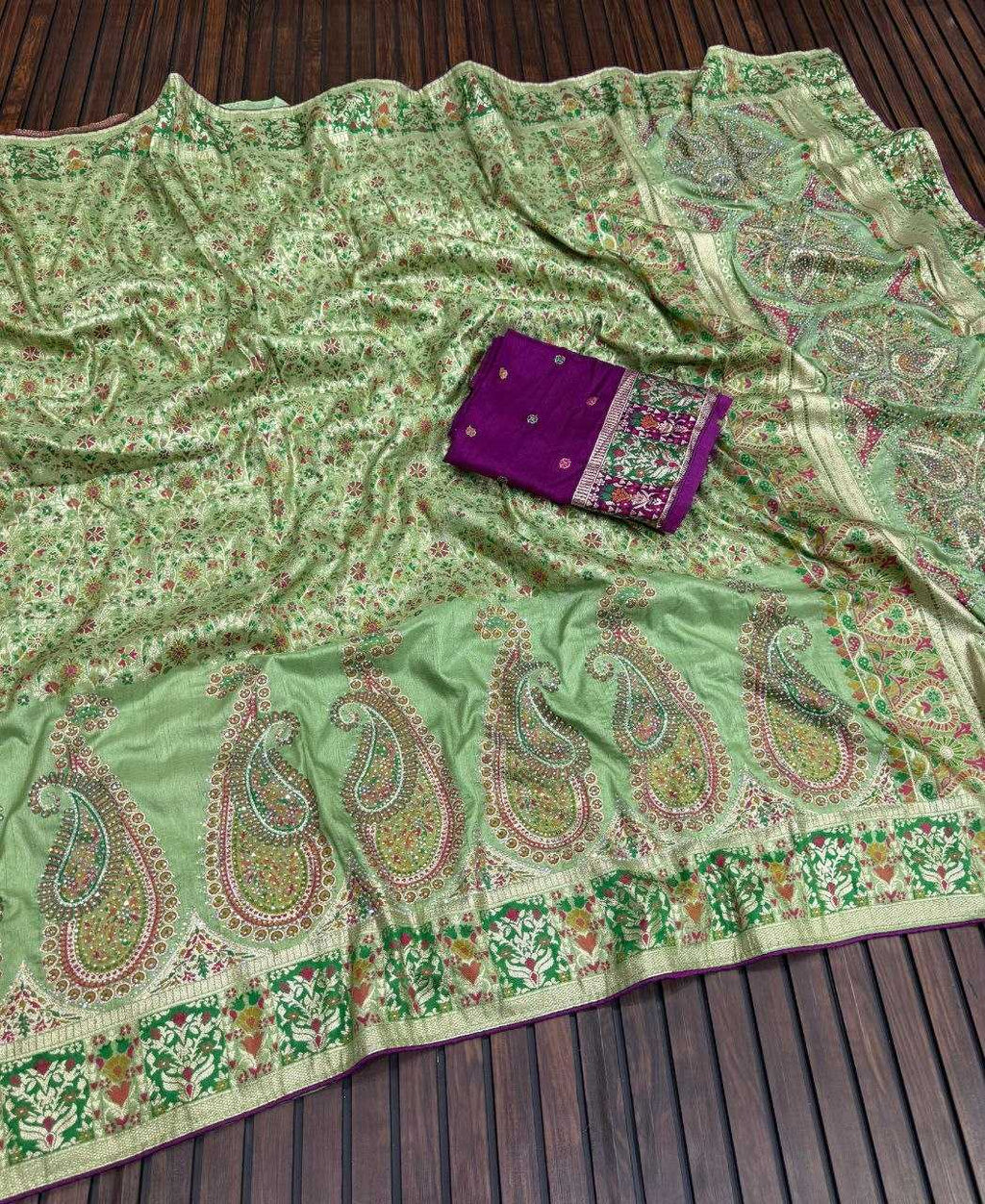 Green paisley patterned fabric with a purple pouch on a wooden surface