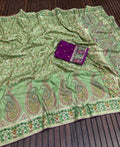 Green paisley patterned fabric with a purple pouch on a wooden surface