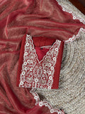 Red garment with white embroidery on a textured surface