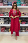 Woman in a red outfit standing in front of shelves with folded fabrics.