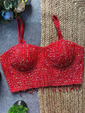 Red beaded top on a textured surface with flowers in the background