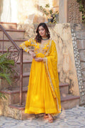 Woman in a yellow traditional outfit standing outdoors on stone steps.