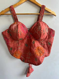 Red embroidered bralette on a wooden hanger against a white background